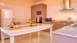 A modern kitchen with a central island, a built-in oven, and a stainless steel range hood. - Sunrise House, a Home in Madeira (Ponta do Sol)