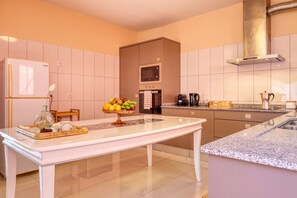 A modern kitchen with a central island, a built-in oven, and a stainless steel range hood. - Sunrise House, a Home in Madeira (Ponta do Sol)