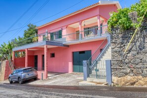 A two-story building with a pink facade, a balcony, and a staircase leading to the upper floor. - Sunrise House, a Home in Madeira (Ponta do Sol)