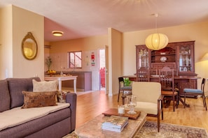 A living room with a sofa, a dining table with chairs, a kitchen area with cabinets, and a large mirror on the wall. - Sunrise House, a Home in Madeira (Ponta do Sol)