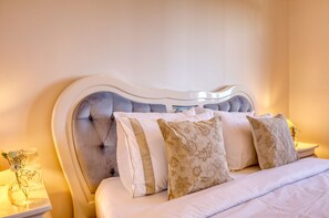 A bed with a tufted headboard, multiple pillows, and a bedside table with a vase of flowers. - Casa do Serrado, a Home in Madeira (Ponta do Sol)