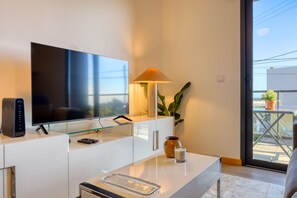 A modern living room with a flat-screen TV, a glass coffee table, a lamp, and a potted plant. - Casa do Serrado, a Home in Madeira (Ponta do Sol)