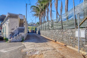A narrow street with a stone wall on one side and a building with a staircase on the other. - Casa do Serrado, a Home in Madeira (Ponta do Sol)
