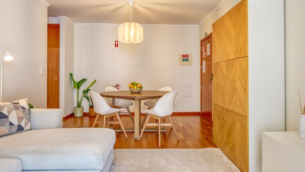 A modern living room with a sofa, a dining table with chairs, a hanging light fixture, and a wooden cabinet. - Cozy Santa Cruz, a Home in Madeira (Santa Cruz)