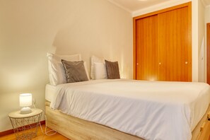 Ein Schlafzimmer mit Bett, Nachttisch, Lampe und einem Holzschrank.