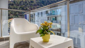 A balcony with a white plastic chair and a small table with a yellow pot of flowers. - Cozy Santa Cruz, a Home in Madeira (Santa Cruz)