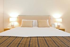A hotel room with a large bed, two bedside tables, and two lamps. - Modern & Comfortable Brand-New 3-Bedroom Apartment with AC and Parking, Near the Metro and Downtown (Porto)