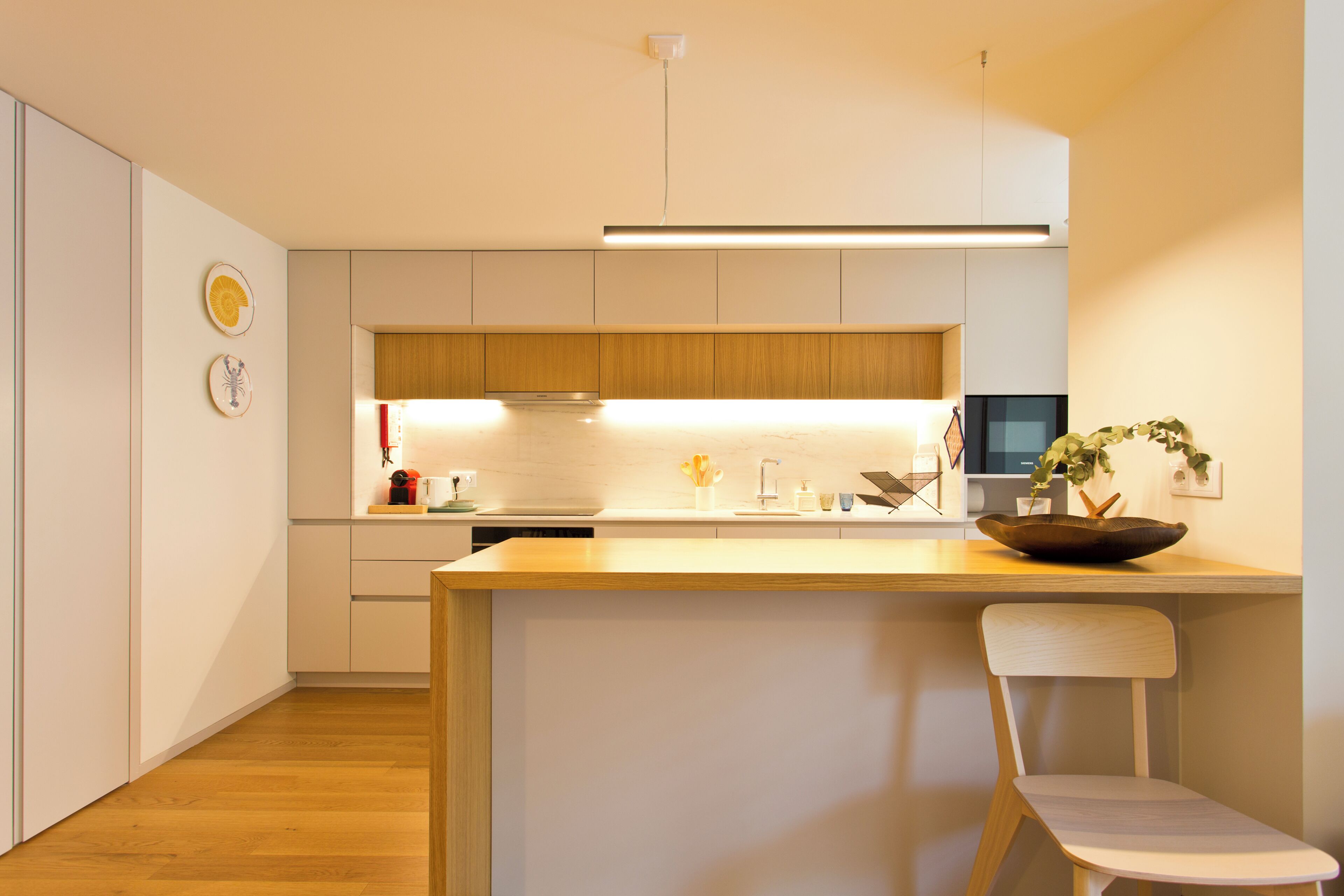 A modern kitchen with a central island, wooden cabinets, and a built-in oven.