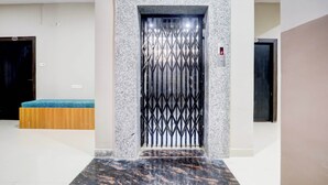 A modern elevator with a geometric metal gate, a marble floor, and a blue bench in the background. - Super Collection O Gola Road (Danapur)