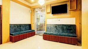 A room with two dark green sofas, a flat-screen TV mounted on the wall, and a chandelier. - Super Collection O Gola Road (Danapur)