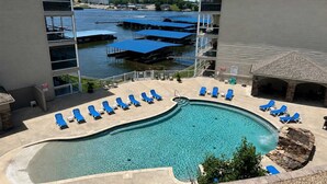 Une piscine avec des chaises longues, une vue sur une rivière et un bâtiment doté d’un balcon.