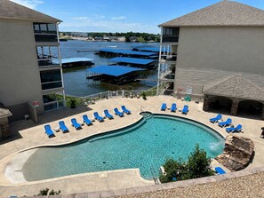 Ein Swimmingpool mit Liegestühlen, Blick auf einen Fluss und ein Gebäude mit einem Balkon.