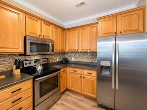 A kitchen with wooden cabinets, stainless steel appliances, a microwave, oven, and a refrigerator. - Eagles Nest at Lands End - Boat Slip! (Osage Beach)