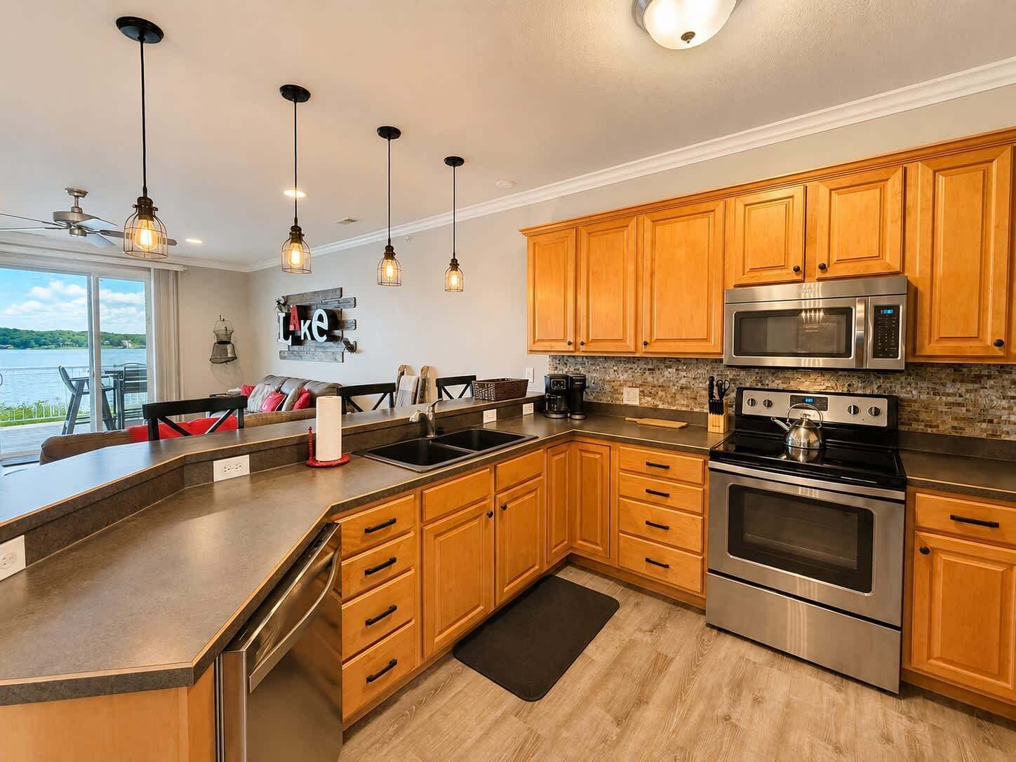 Une cuisine moderne avec des meubles en bois, des appareils électroménagers en acier inoxydable et des luminaires suspendus.