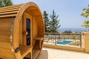 Un sauna en bois avec vue sur une piscine et la mer.