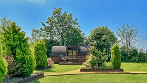 Un jardin bien entretenu, agrémenté d’une terrasse en bois, d’un petit chalet et de diverses espèces d’arbres.
