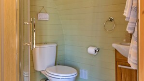 Une salle de bain comprenant des toilettes, un espace douche et un lavabo avec un porte-serviettes.