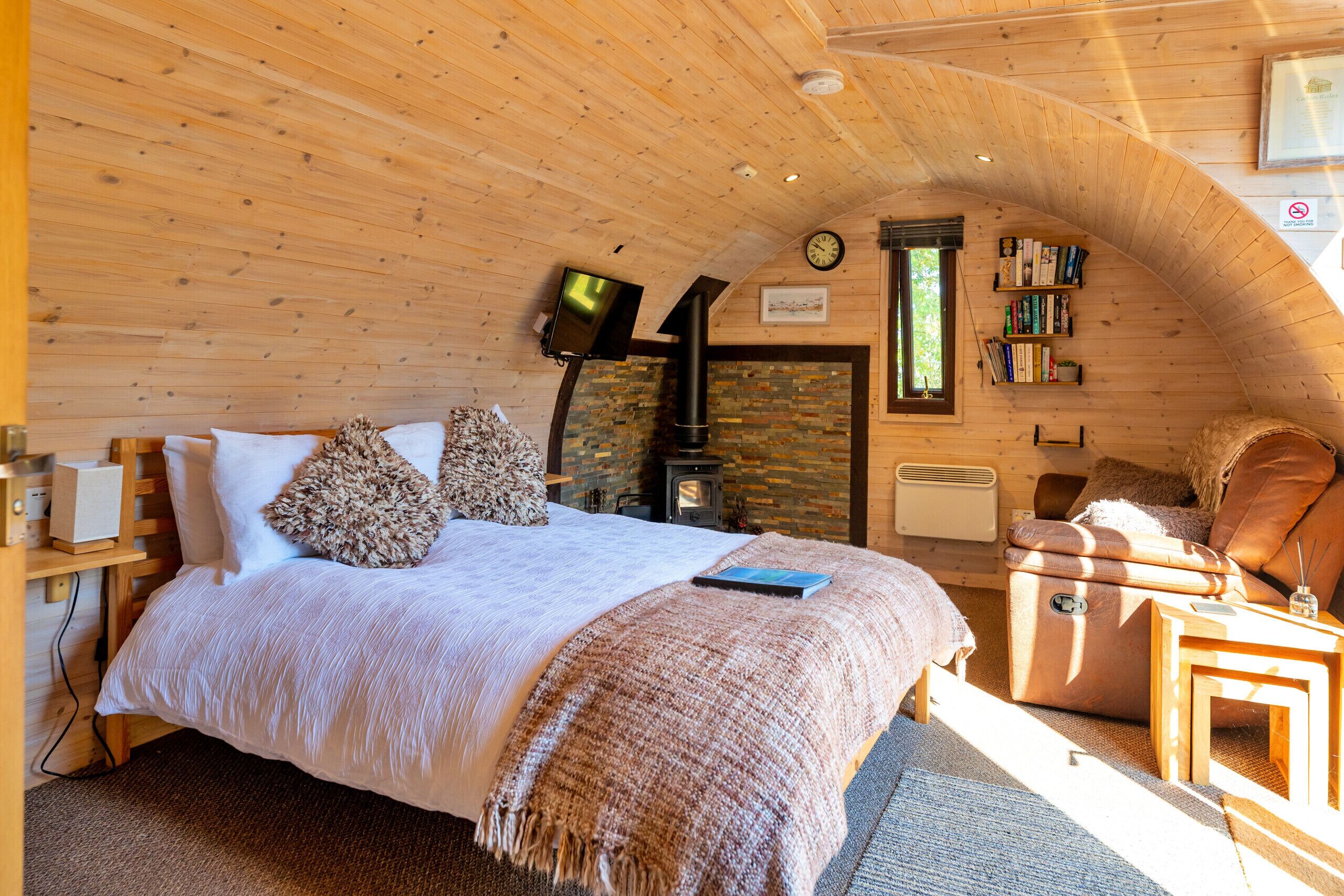 Un dormitorio acogedor con cama, chimenea, estantería y ventana.
