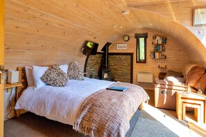 Ein gemütliches Schlafzimmer mit Bett, Kamin, Bücherregal und Fenster.