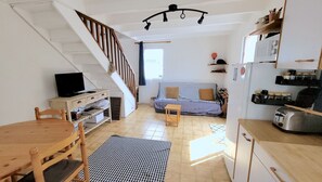 Ein kompakter Wohnraum mit Treppe, einer Sitzecke, einem Essbereich und einer Küchenzeile.