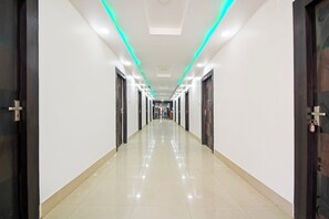 Un pasillo largo e iluminado con puertas a ambos lados, que conduce a un área central con una lámpara en el techo.