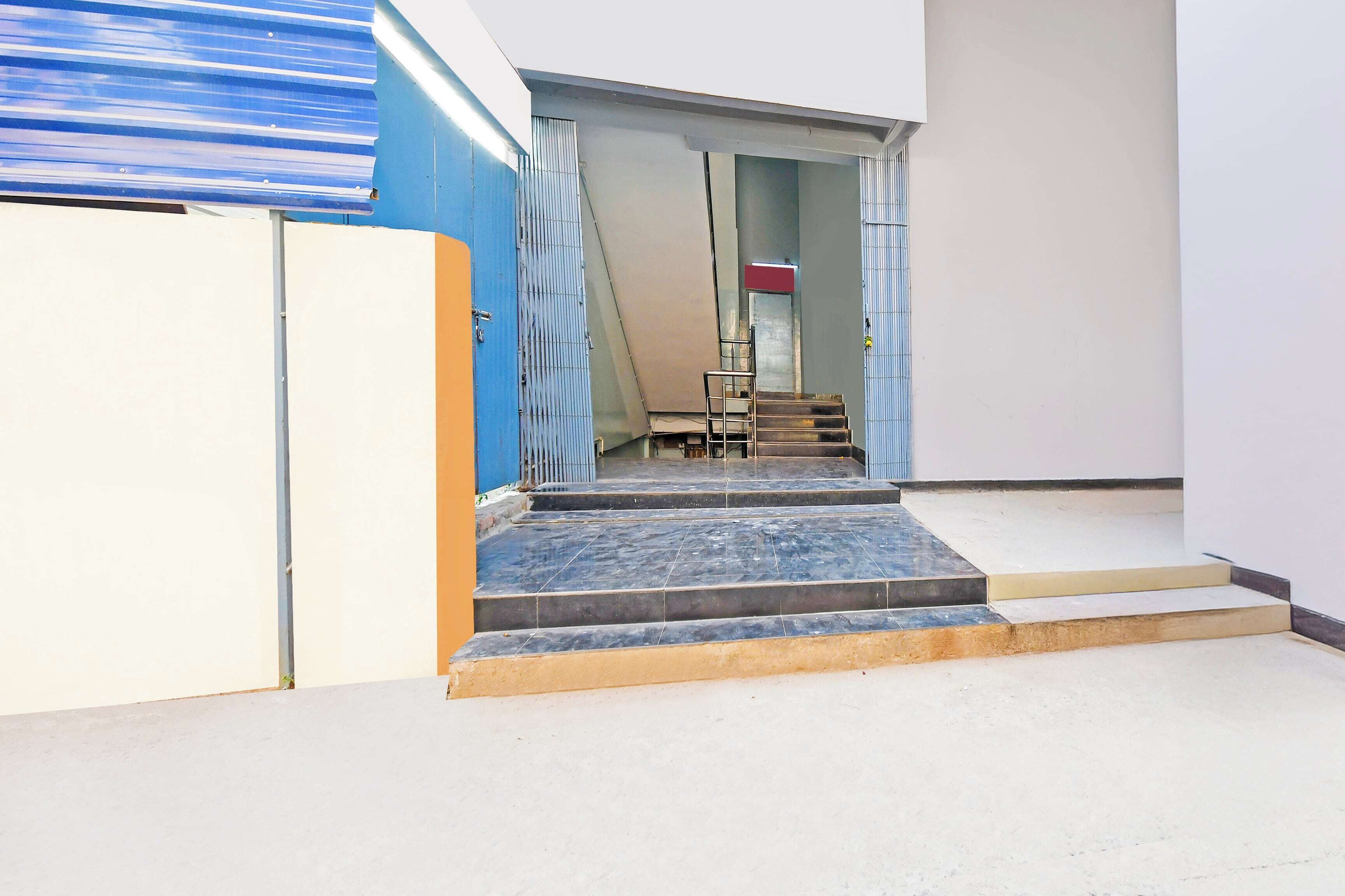 Un escalier extérieur menant à une porte surmontée d’un portail en métal.