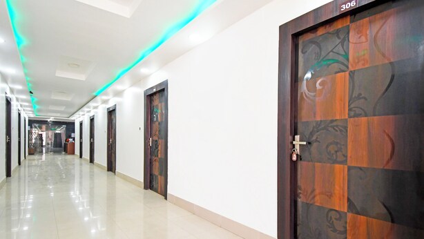 Um corredor de hotel com várias portas, piso ladrilhado e teto com iluminação embutida.