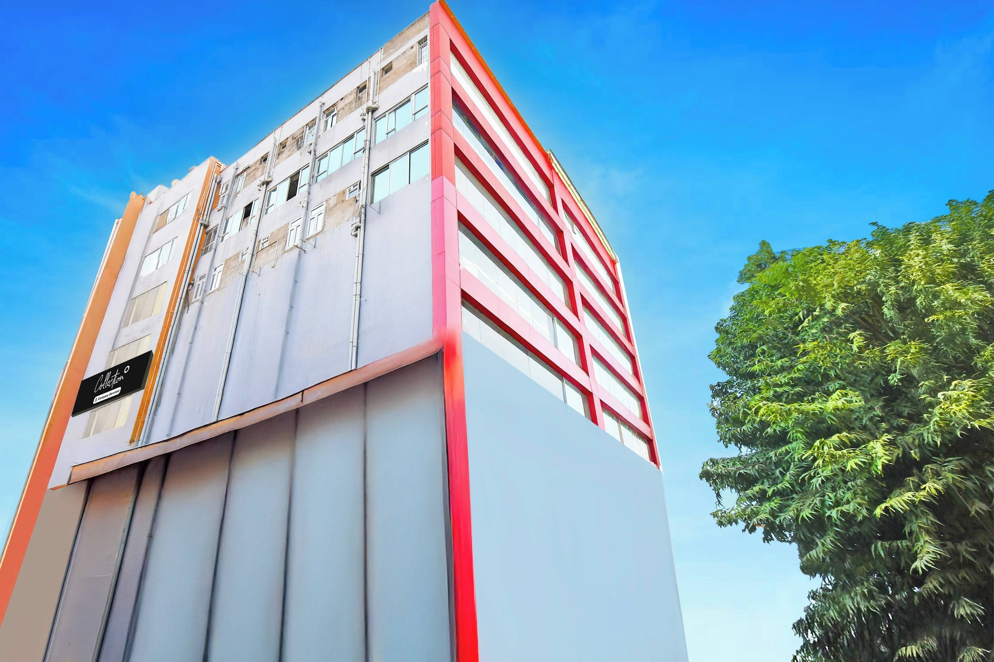 Un edificio de varios pisos con un diseño arquitectónico moderno, que destaca por una llamativa combinación de colores rojo y blanco.
