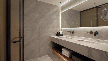 A modern bathroom with a glass shower door, a large mirror, and a vanity with a sink and towel storage.