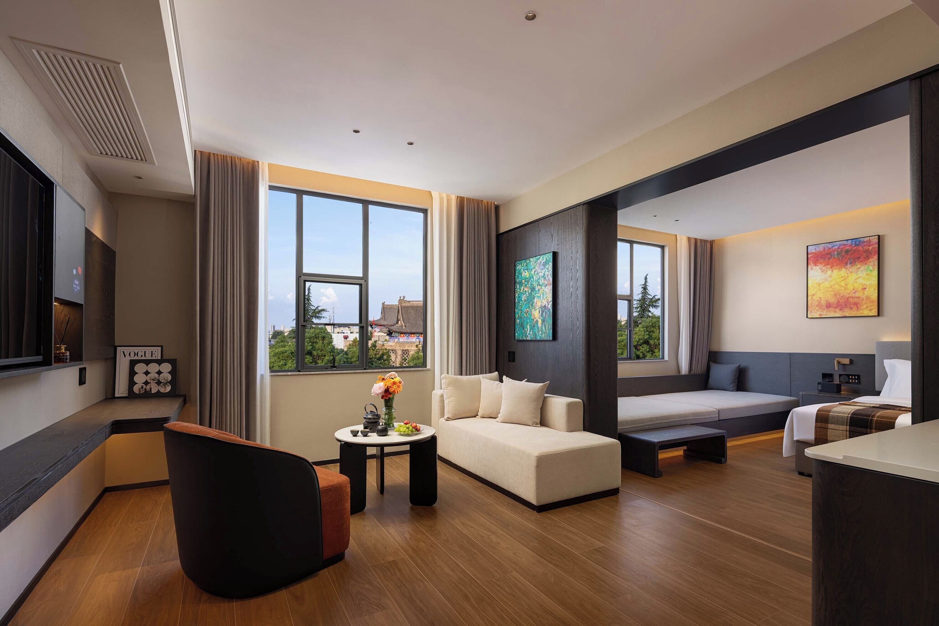 Una habitación de hotel moderna con sofá, cama, escritorio y televisor.