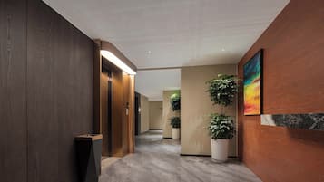 Un pasillo moderno con pared de madera, un cubo de basura, una planta en maceta y un cuadro.