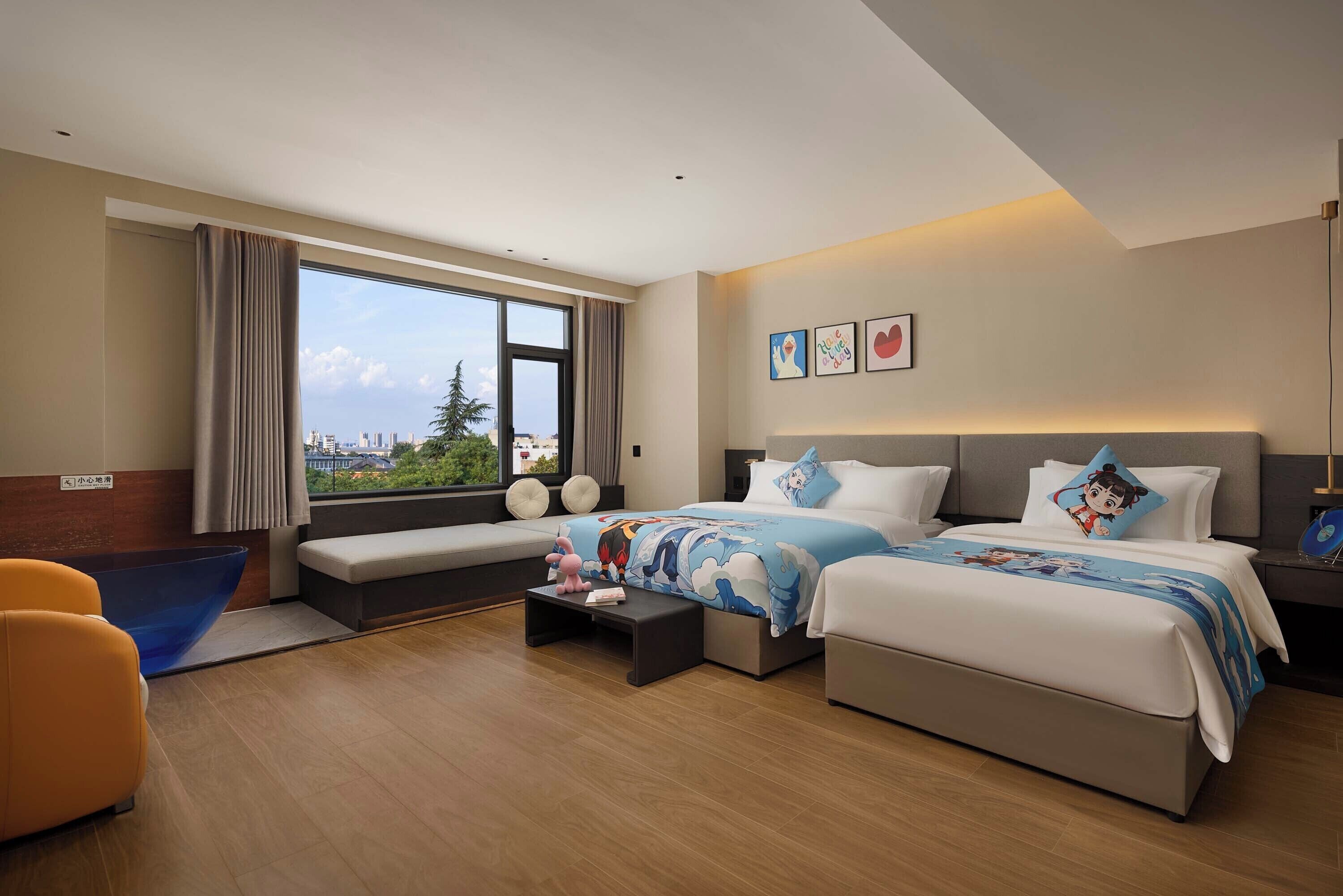 A hotel room with a large bed, a sofa, a small table, and a view of the city.
