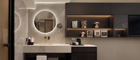 Une salle de bain moderne avec un meuble-lavabo en marbre, un miroir rond et une étagère où sont posés des livres et des objets décoratifs.