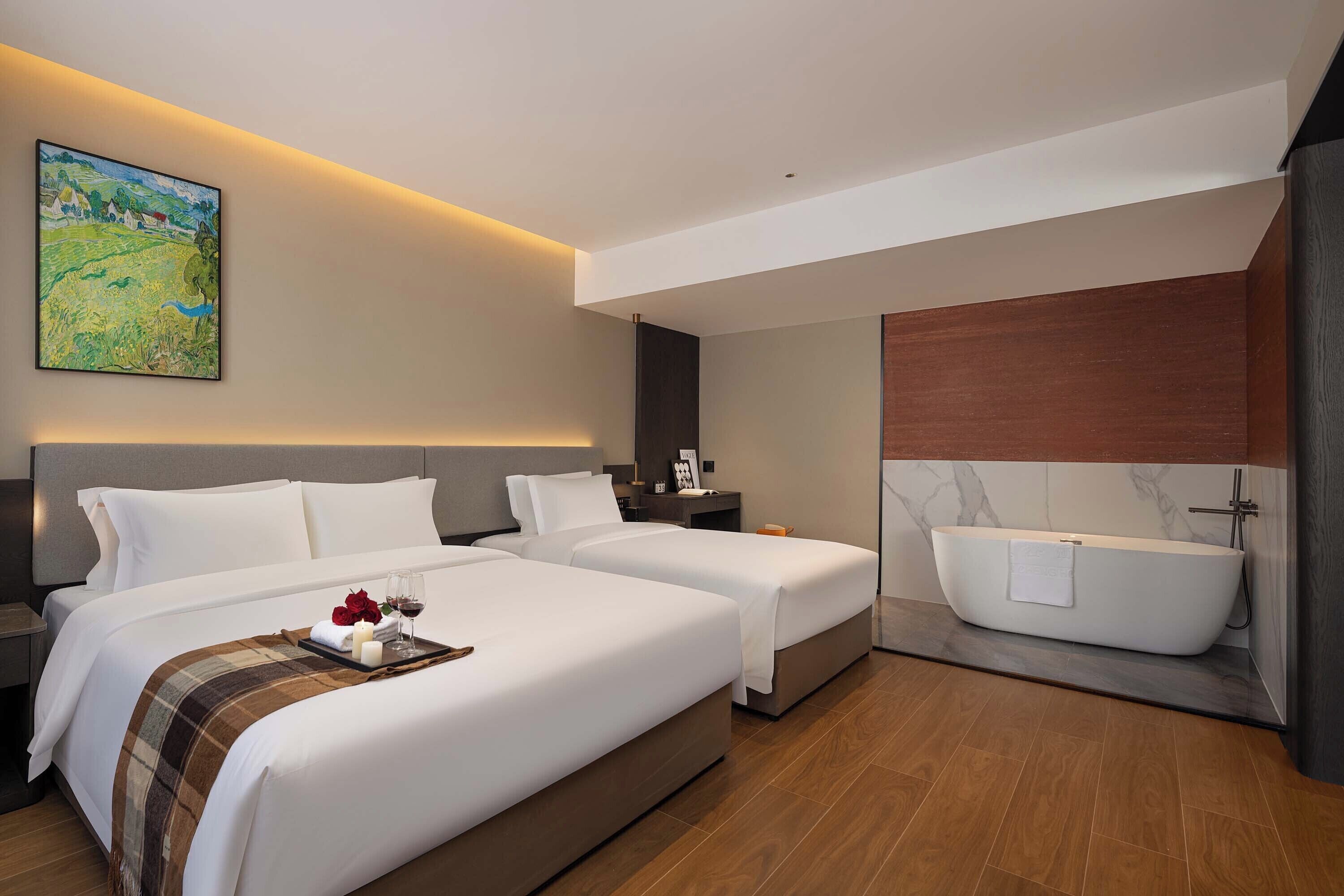 Habitación de hotel con dos camas, una bañera grande y un cuadro en la pared.
