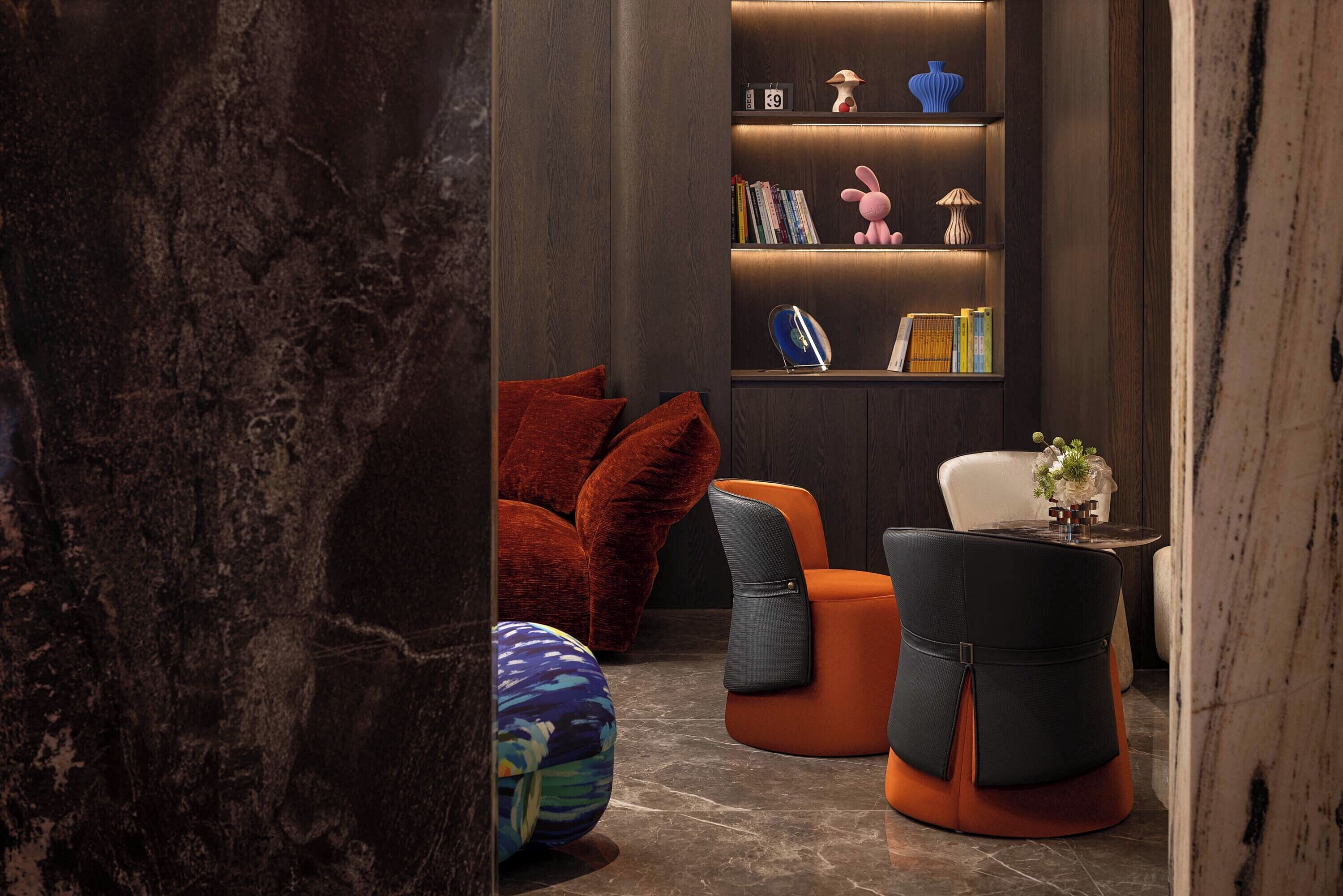 A modern interior with a dark wood bookshelf, plush seating, and decorative items.