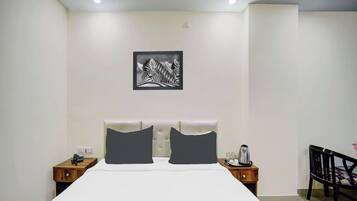 Ein Hotelzimmer mit einem großen Bett, zwei Nachttischen, einem Sessel, einer Kaffeemaschine und einem gerahmten Bild an der Wand.
