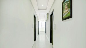 A long, narrow hallway with white walls and a glossy floor, leading to a bright room at the end. - Collection O Rajeev Nagar Near Atal Path (Patna)
