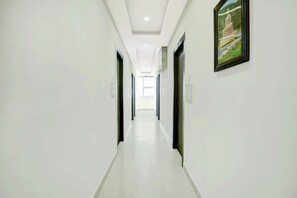 A long, narrow hallway with white walls and a glossy floor, leading to a bright room at the end. - Collection O Rajeev Nagar Near Atal Path (Patna)