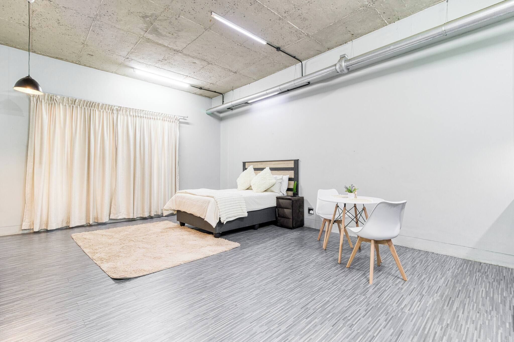Une chambre moderne avec un lit, une table de chevet et une petite table blanche avec des chaises.