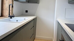 Eine moderne Küche mit grauen Schränken, einer weißen Arbeitsplatte und einem Holzboden.