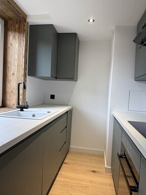 A modern kitchen with grey cabinets, a white countertop, and a wooden floor. - The Courchevel Nests: LA LOGE, Le Praz (Courchevel)