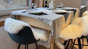 Ein Essbereich mit Tisch für zwei Personen, Blick ins Freie durch ein Fenster und ein Holzmast im Hintergrund.