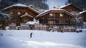 Eine Holzhütte mit Holzzaun vor verschneiter Landschaft.