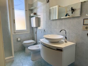A bathroom with a toilet, bidet, and a sink with a vessel basin. - Casa Uccia Artallo (Imperia)