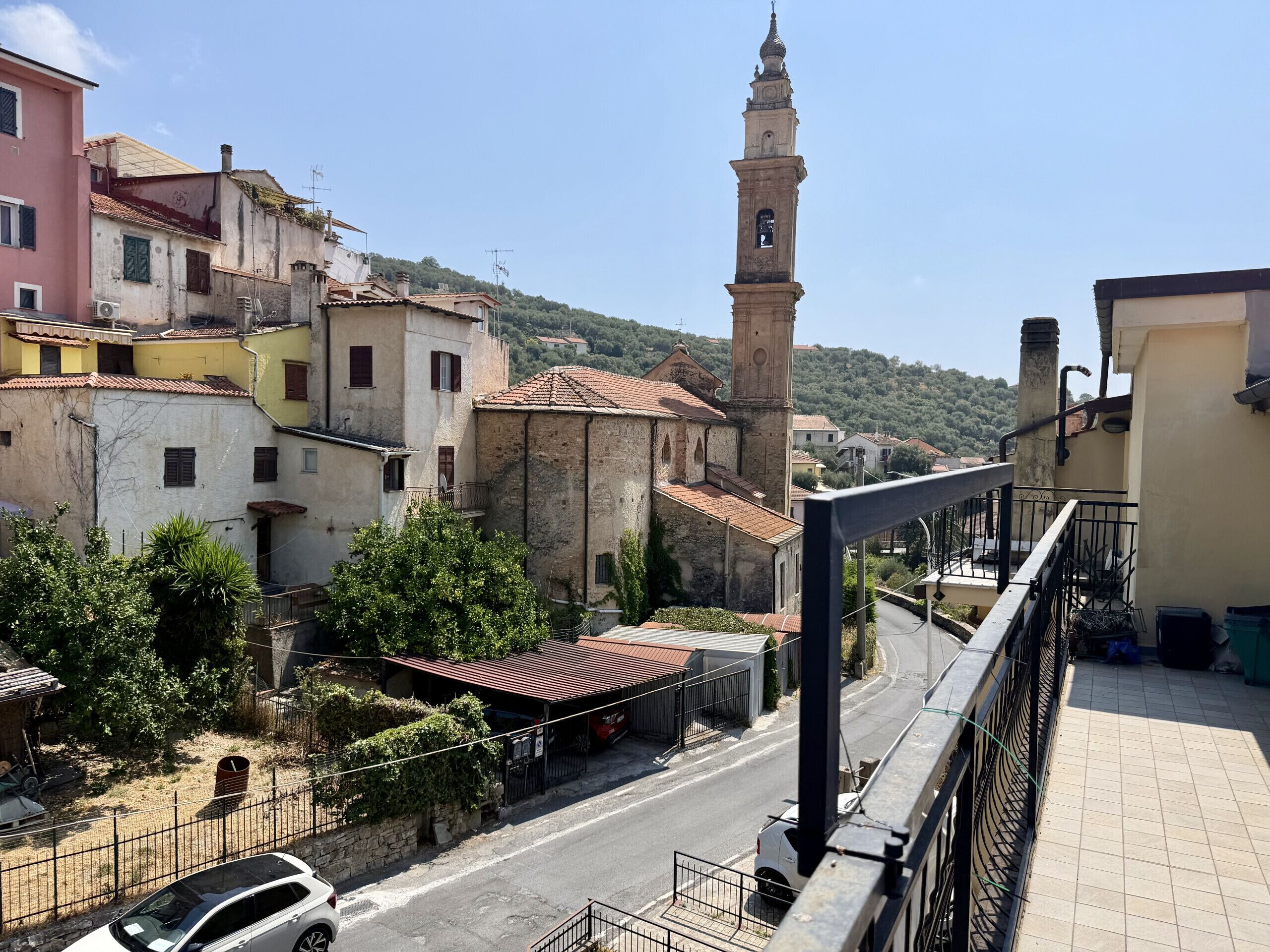 A street view with buildings, a mosque with a minaret, and a car parked on the side.