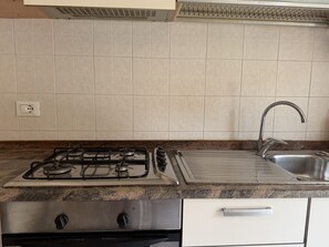 A kitchen with a gas stove, a stainless steel sink, and a granite countertop. - Casa Uccia Artallo (Imperia)