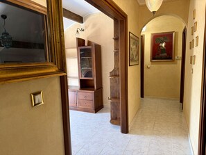A hallway with a wooden cabinet, a tiled floor, and a door with a mirror. - Casa Uccia Artallo (Imperia)
