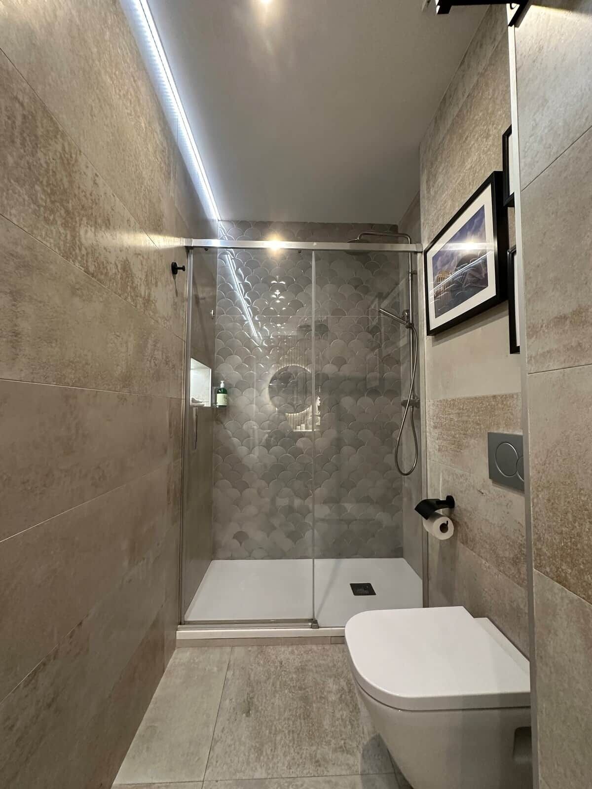 Une salle de bain moderne avec une douche à parois de verre, des toilettes et un tableau encadré au mur.