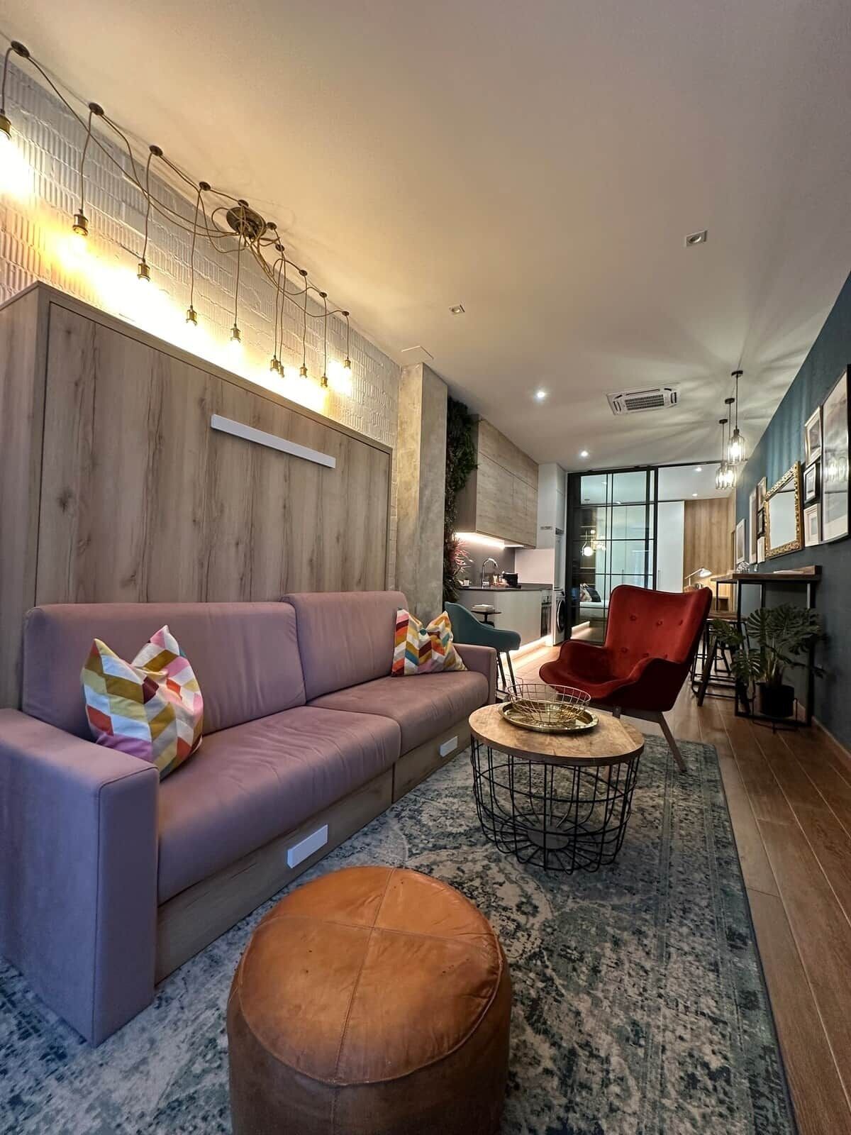 A modern living room with a sofa, ottoman, and red chair.