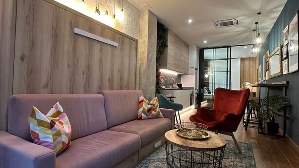 A modern living room with a sofa, ottoman, and red chair. - Magnificent brand-new home next to Plaza España (Valencia)